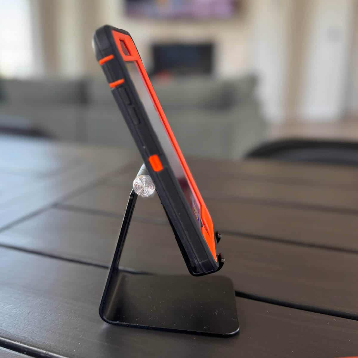 Image of a phone stand sitting on a table with a couch and fireplace in the background.