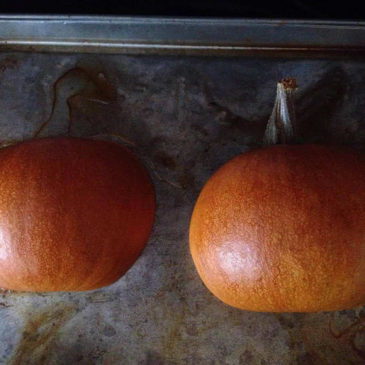 Cooked pumpkin halves on a baking sheet.