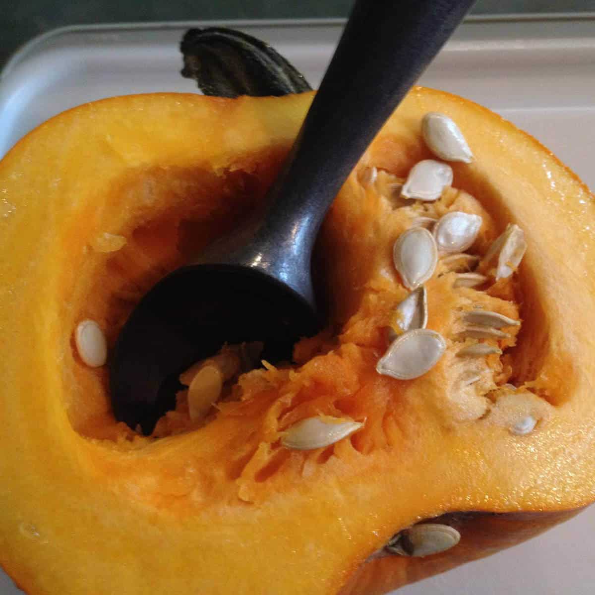 Scooping the guts out of a pumpkin with an ice-cream scoop.