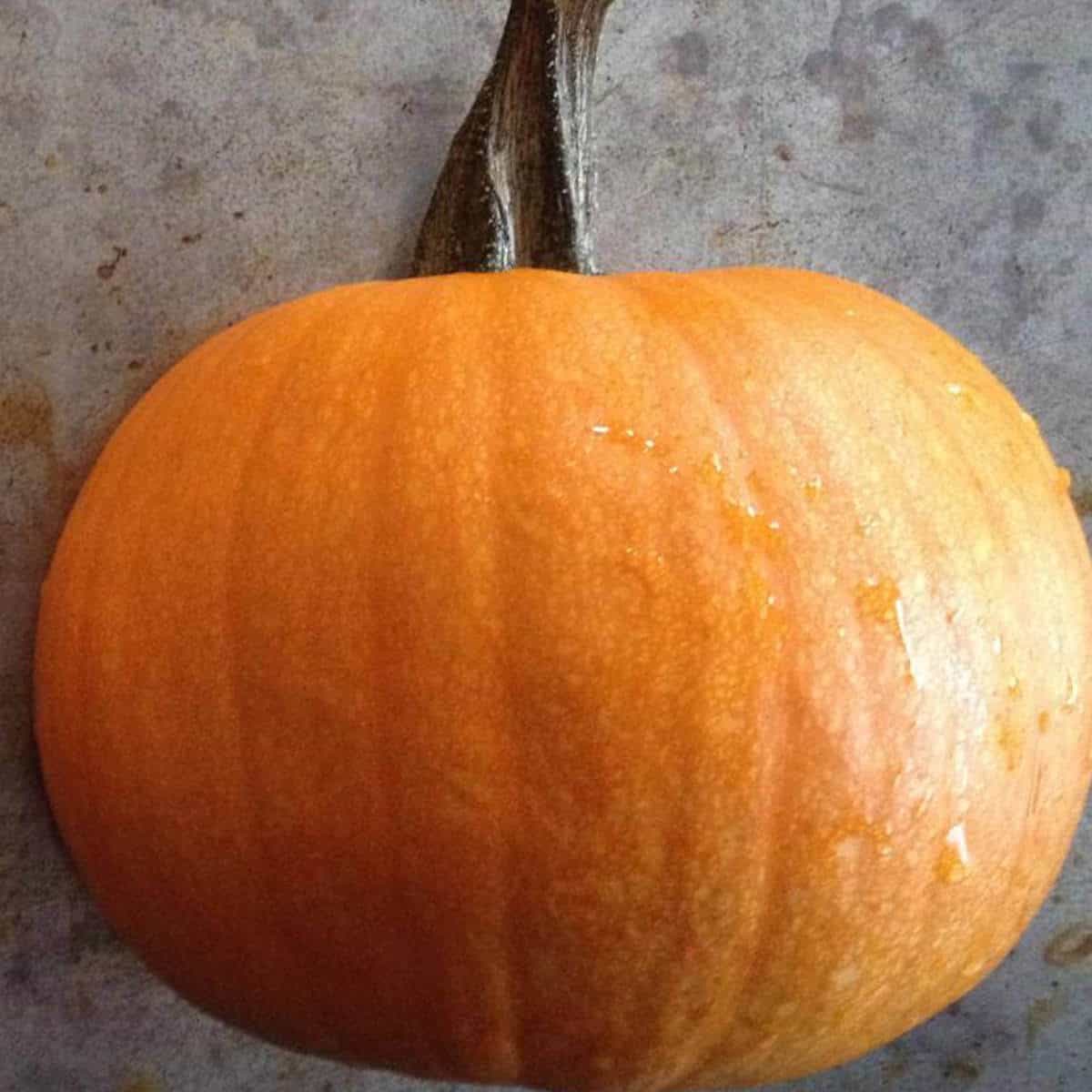 Half a pumpkin, face down on a cooking sheet.