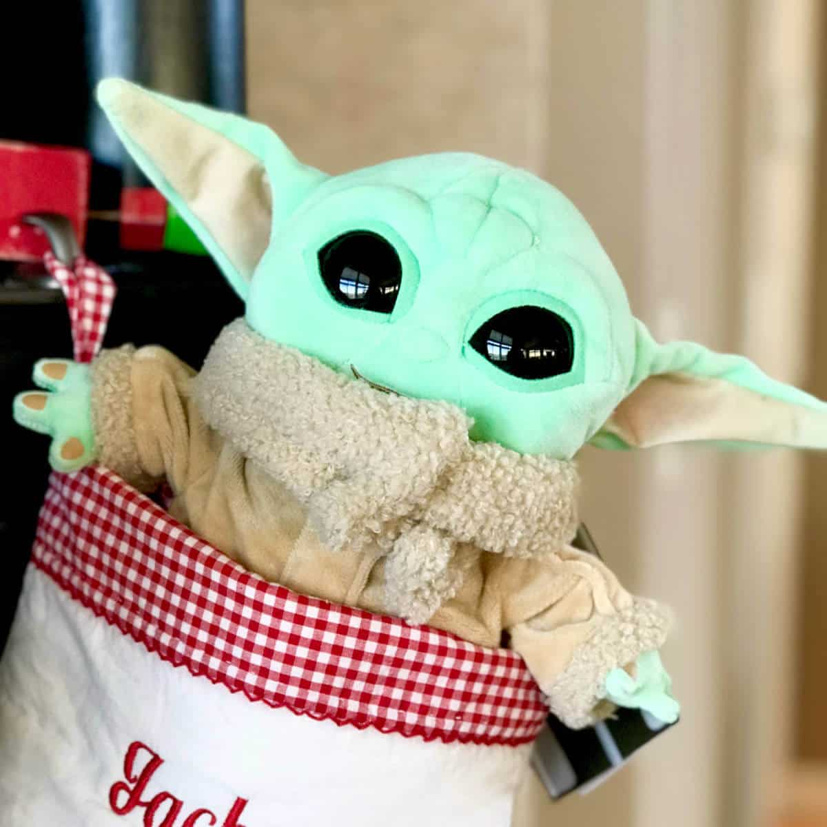 Picture of Baby Yoda sticking out the top of a Christmas stocking.