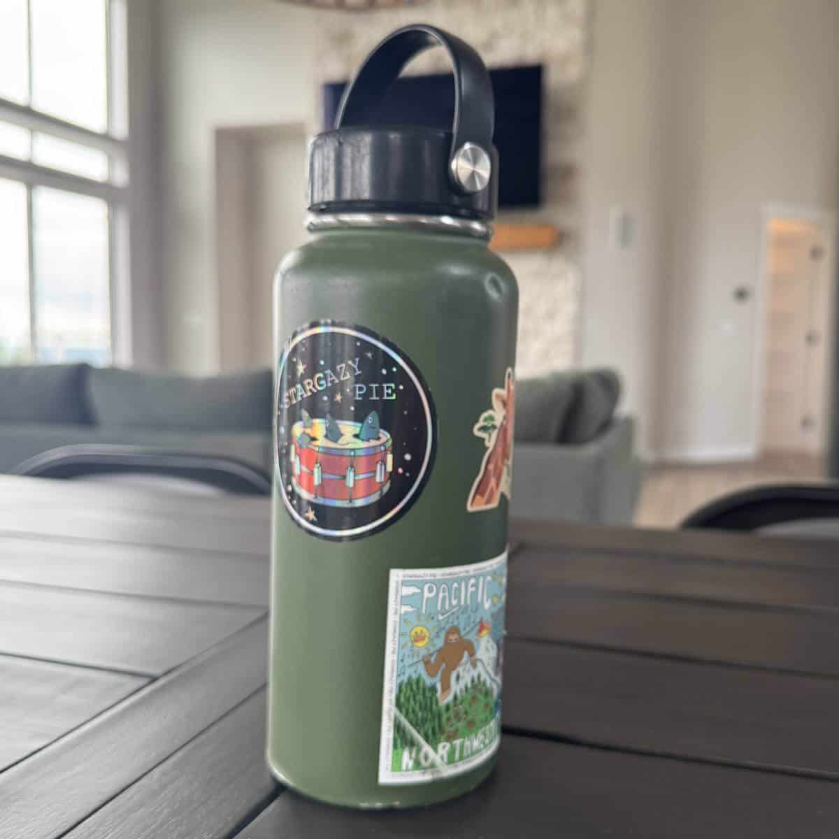Image of a green Hydro Flask with stickers on it sitting on a table.