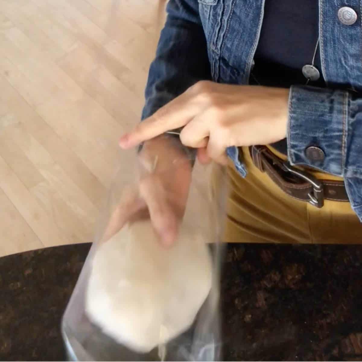 Girl placing a white paper streamer snowball into a clear treat bag.