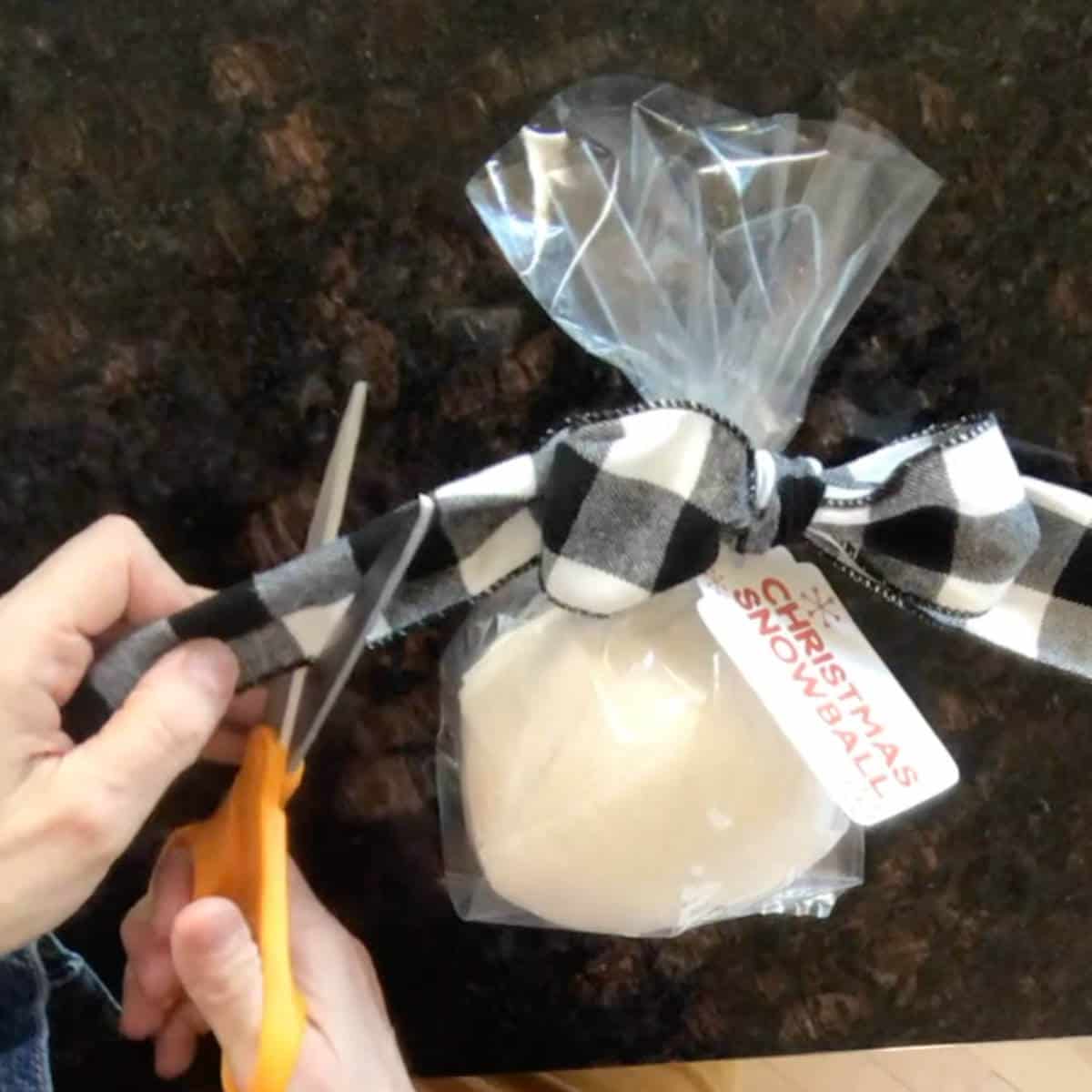 Woman cutting black and white bow ends on a Christmas snowball.