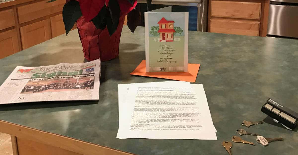 Letter, card, keys, local newspaper, and a poinsetta sitting on a counter for the new homeowner.