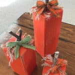 Three pumpkins crafted out of a 4 x 4 wood post and sitting on a coffee table.