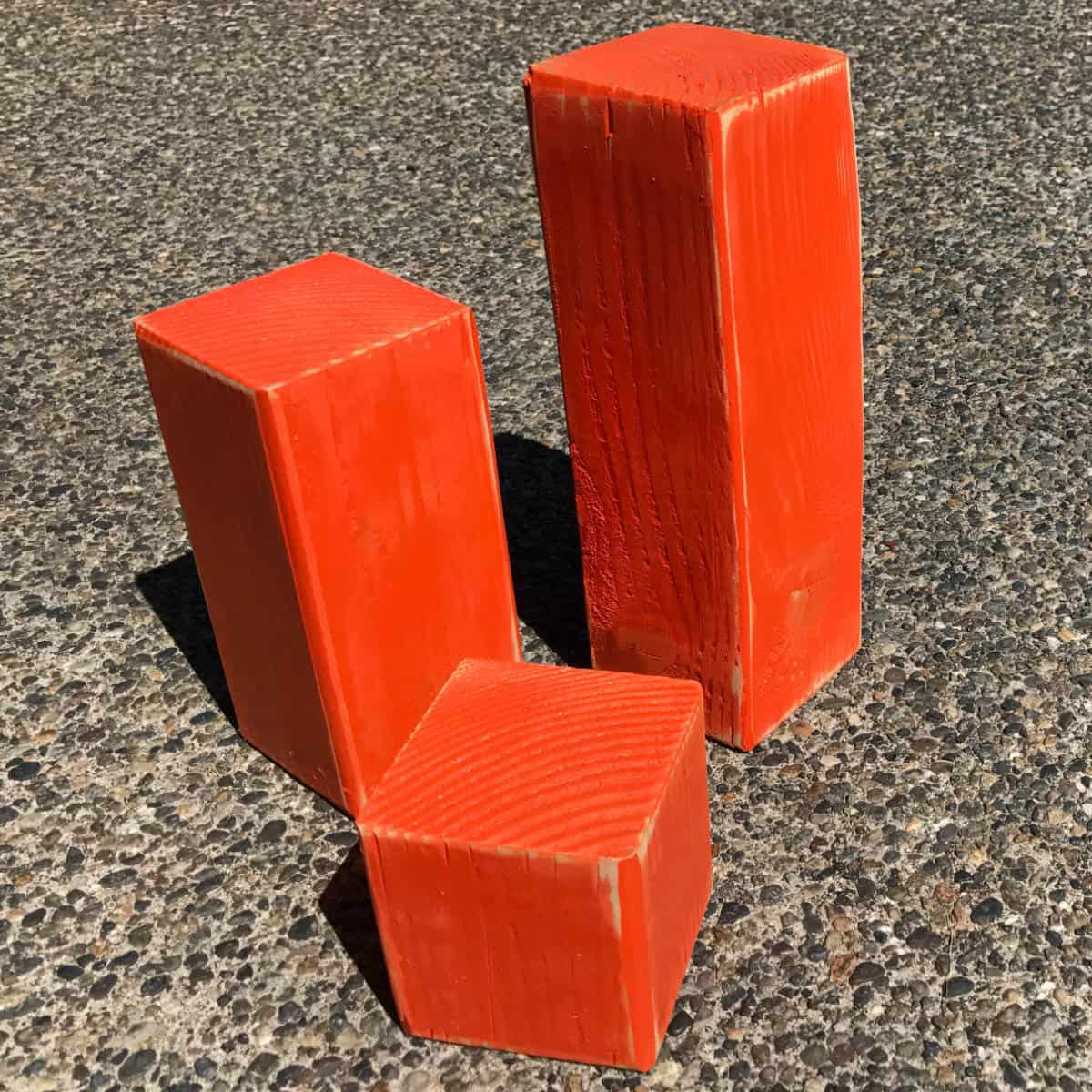 Three pieces of a 4 x 4 wood post painted bright orange.