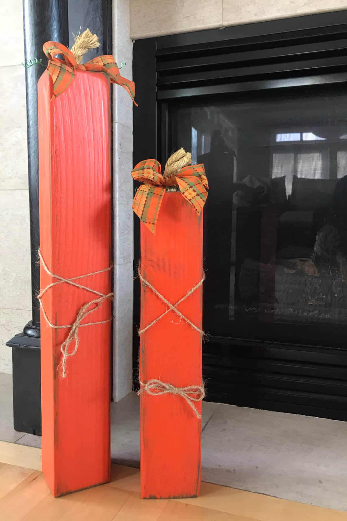 Tall 4 x 4 pumpkins placed next to the fireplace.