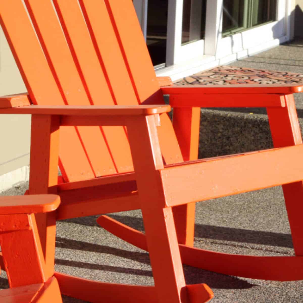 Wooden rocking chair painted orange and sitting on a patio.