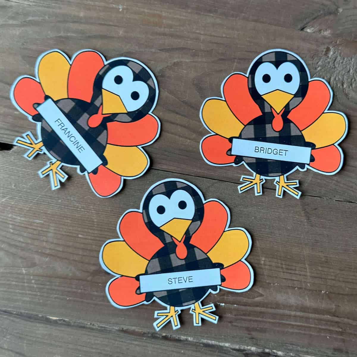 Three turkeys with names on them that have been printed and cut to use as place cards.