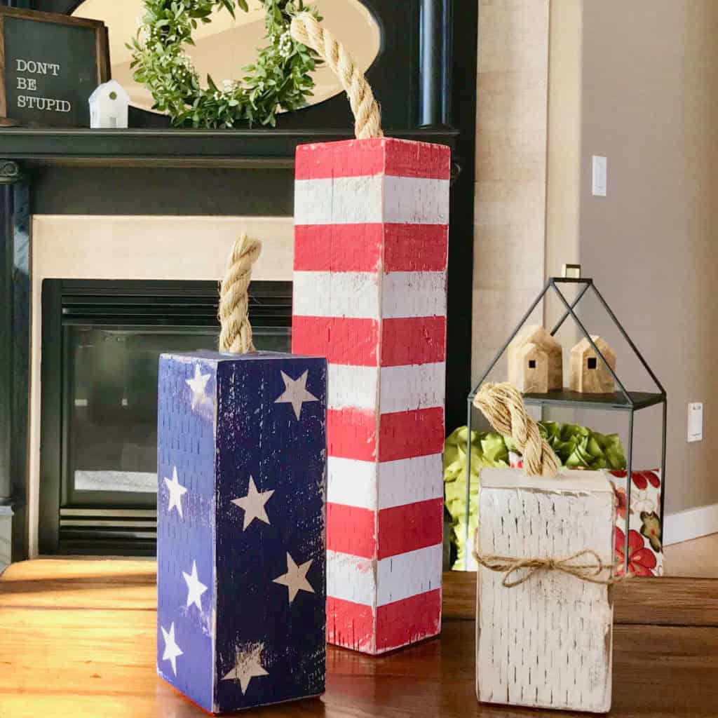 Firecrackers made out of 4 x 4 wood sitting on a coffee table in the living room. One is striped, one has stars, and one is white.