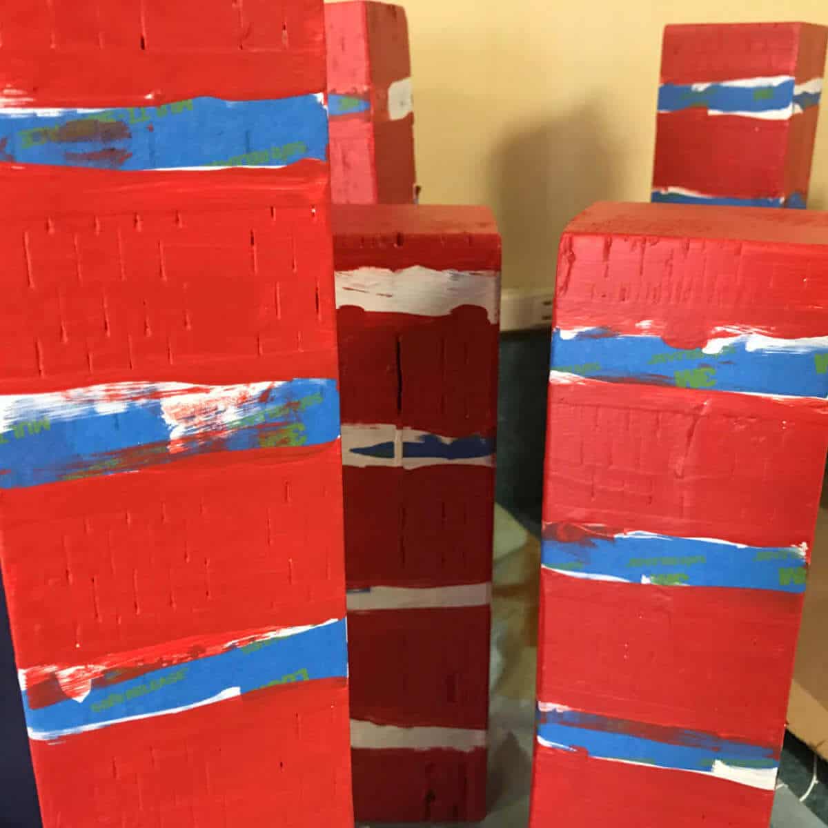 Red stripes painted on 4 x 4 blocks using blue painter's tape.