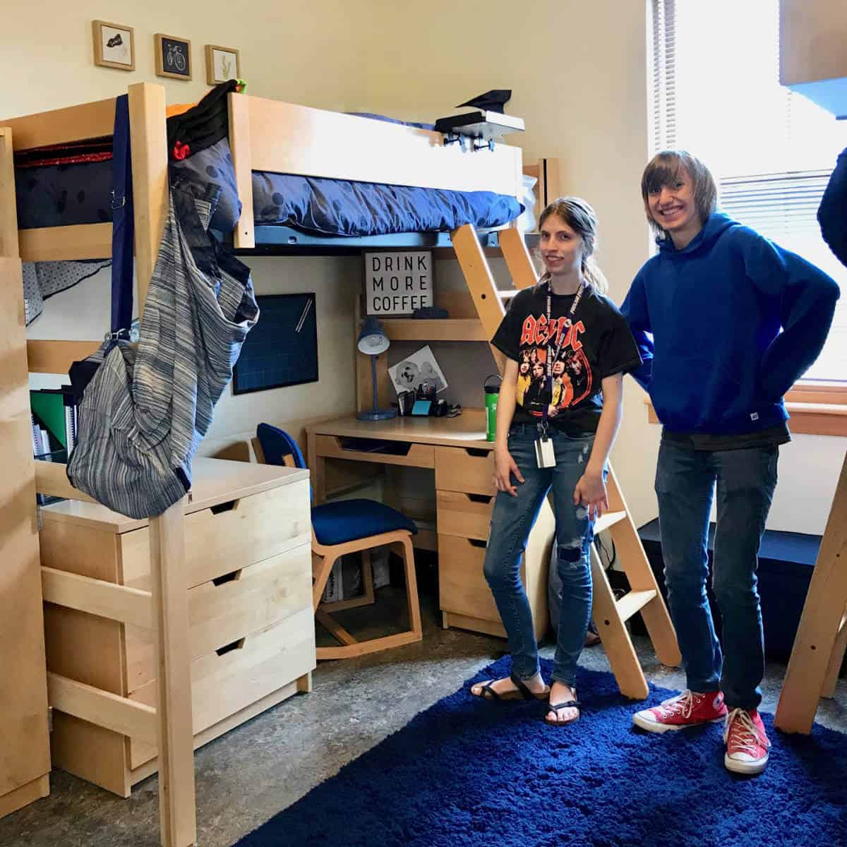 Image of a college student standing in her dorm room with her brother.