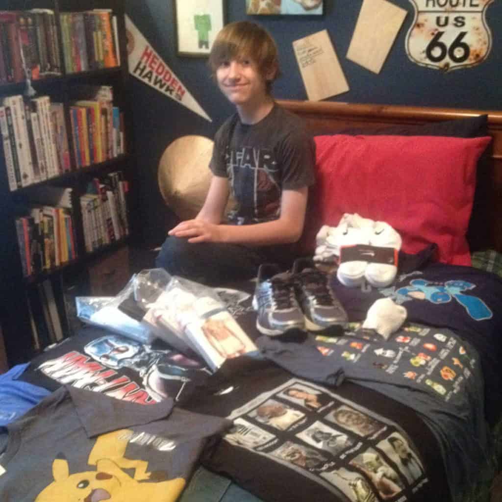 Boy sitting on a bed with new back-to-school clothes.