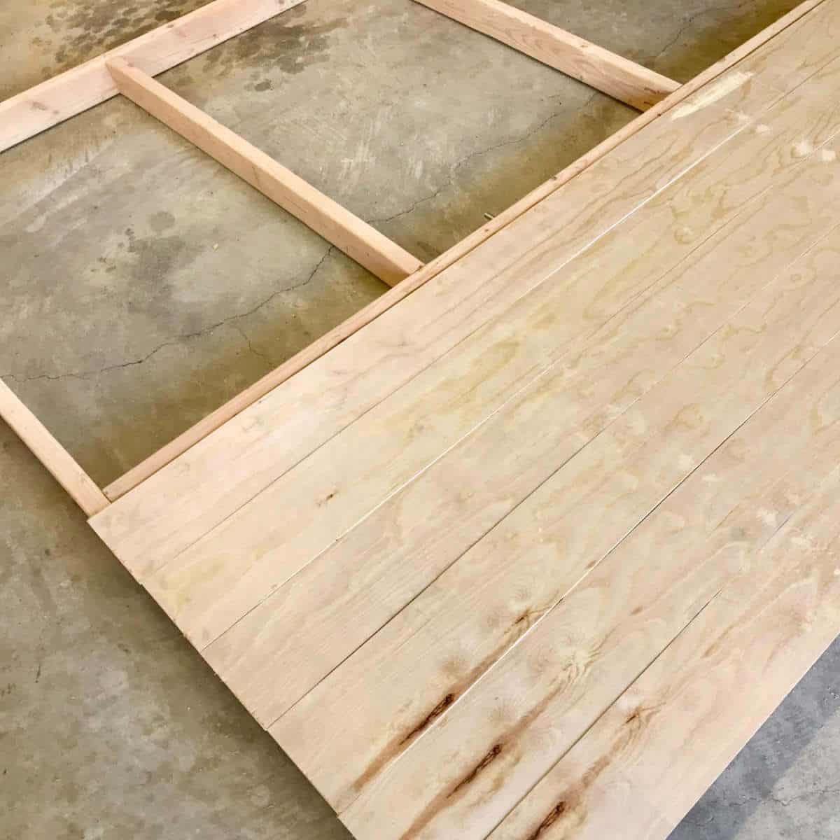 Placing plywood slats on a 2 x 4 frame to build a backdrop wall.