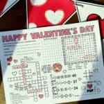 Valentine activity sheet that is partially filled out and laying on a table with a Valentine banner in the background.