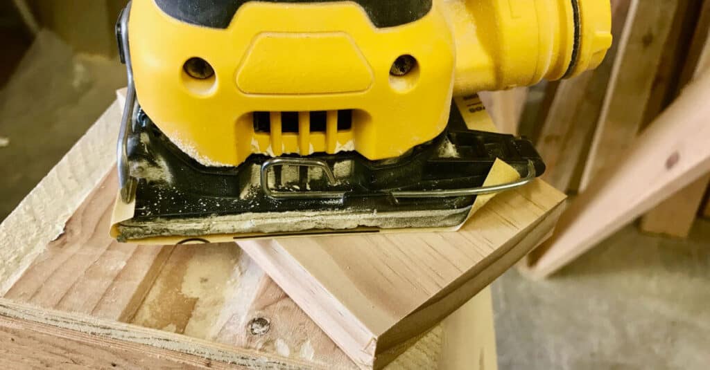 Sanding 1 x 4 piece of wood to prep for paint