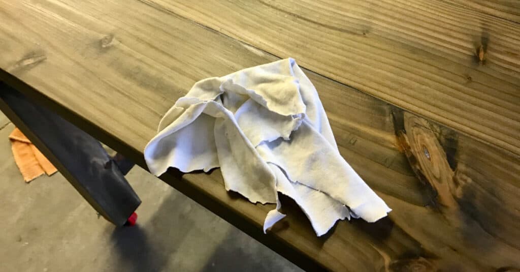 Using a rag to apply wax as a table finish.