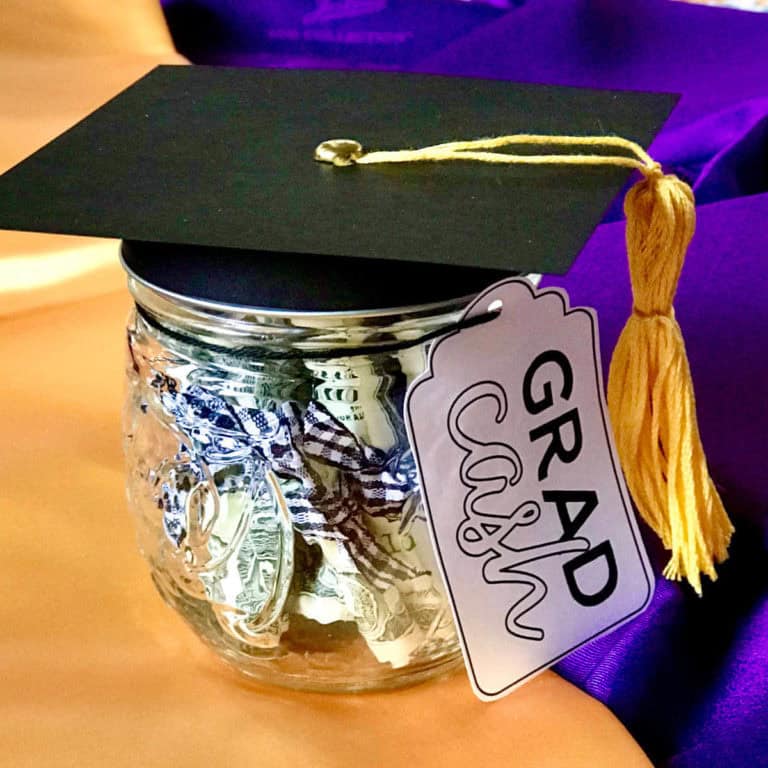 Image of a small jar filled with rolled bills with a grad cash gift tag and a black paper graduation cap on the top.