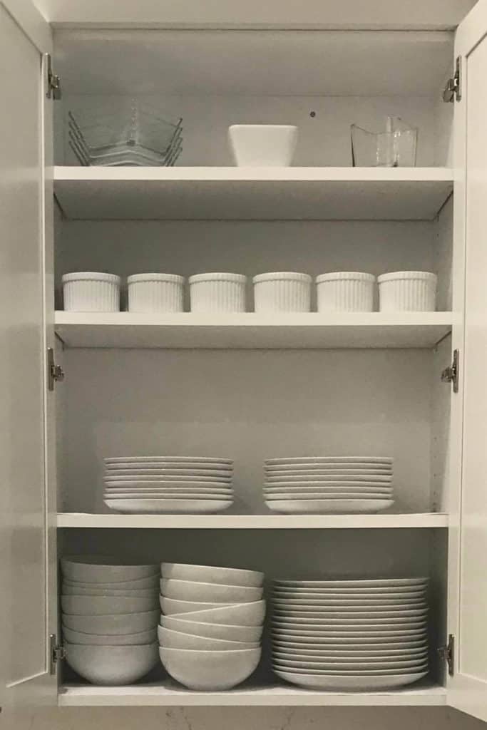 White dishes organized in a cupboard.