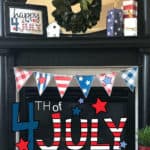 Printable 4th of July banner hung on a fireplace mantel with a Happy 4th of July Sign and 4 x 4 firecrackers on the mantel.