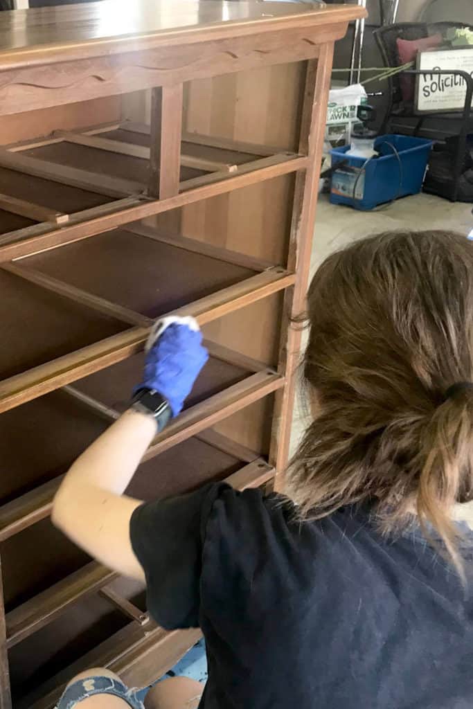 Justine, rubbing Krud Kutter Gloss-Off on the chest of drawers to prep it for paint.