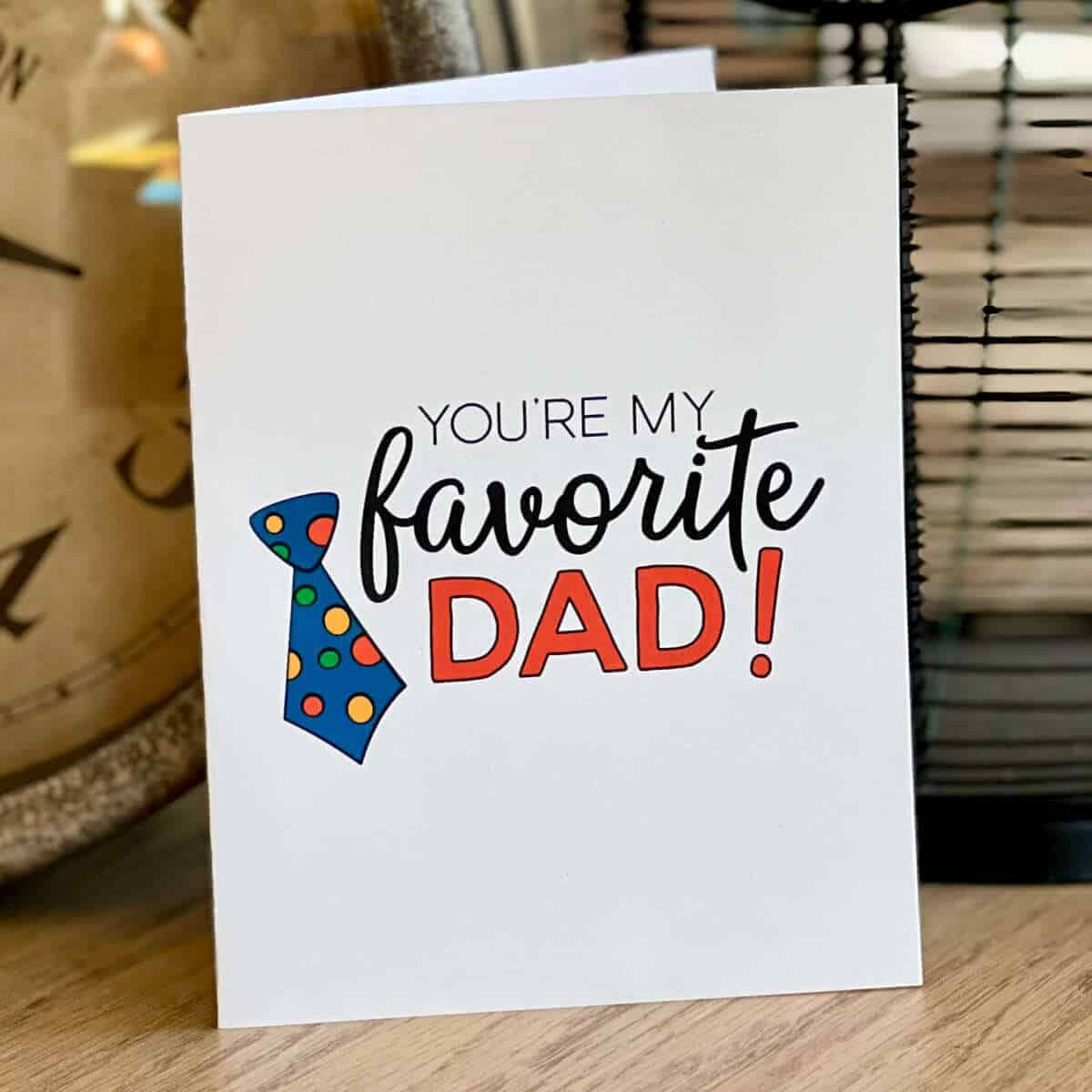 A Father's Day card that says You're My Favorite Dad sitting on a table next to a clock.