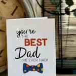 Father's Day card that says You're The Best Dad I've Ever Had sitting on a table next to a clock.