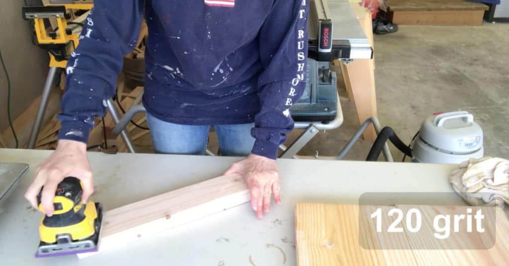 Sanding a small bench leg with 120 grit sandpaper.