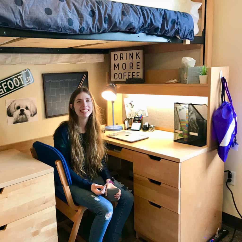 Justine sitting at her desk in her college dorm room.