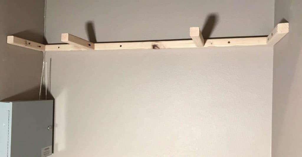 Floating shelf bracket attached to the wall in a coat closet.