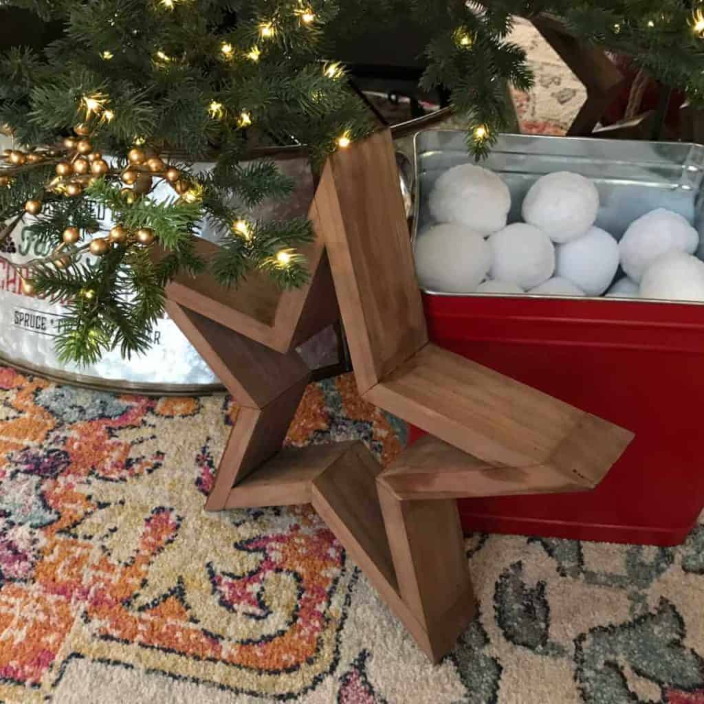 DIY wood star next to a Christmas Tree and a bucket of fake snowballs.