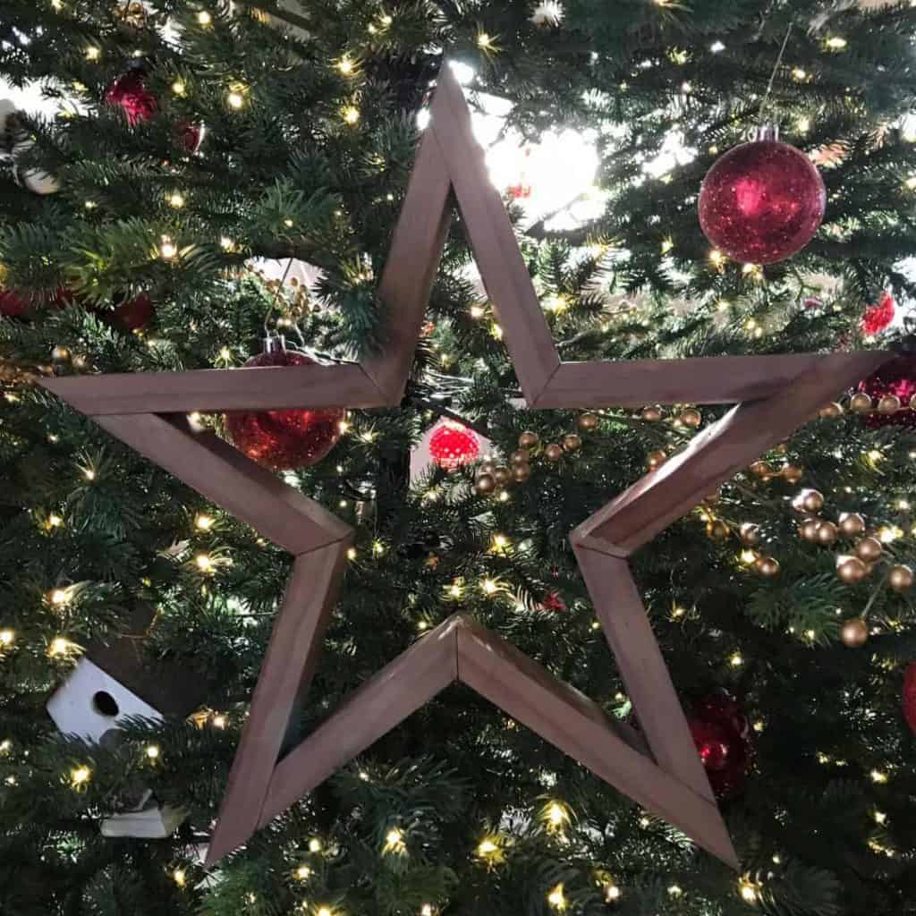 DIY wooden star placed on a Christmas tree.