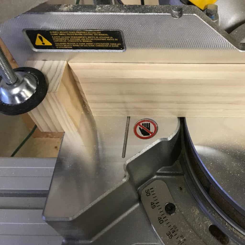 Block placed on miter saw to cut 5 boards.