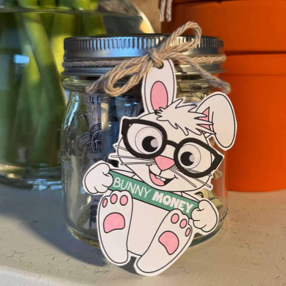 Small jar full of rolled bills with a printable Easter Bunny tied to the lid.