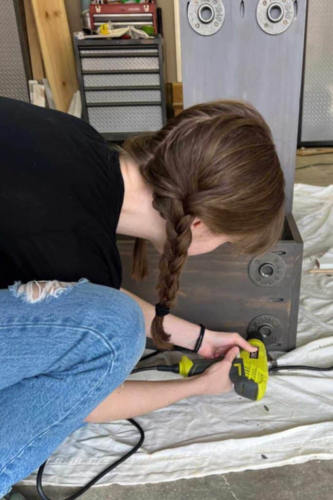 Attaching iron flanges on the bottom of a DIY corner bookshelf to attach pipe legs to.