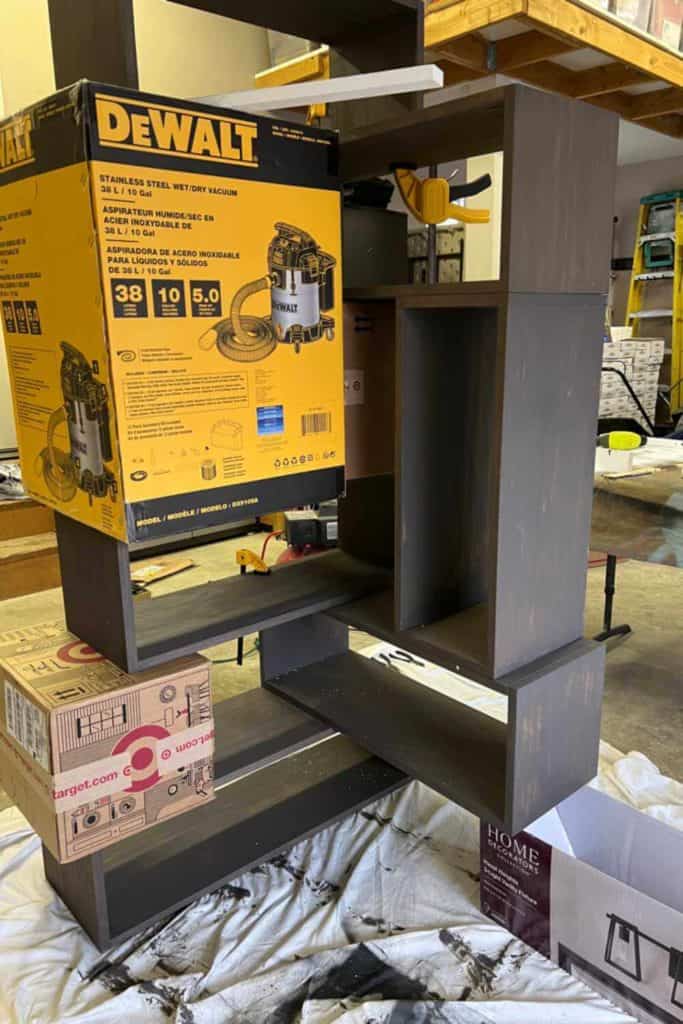 Bracing our DIY bookcase with cardboard boxes.