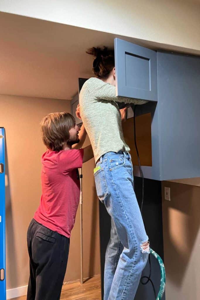 Justine and Jack installing kitchenette cabinets.