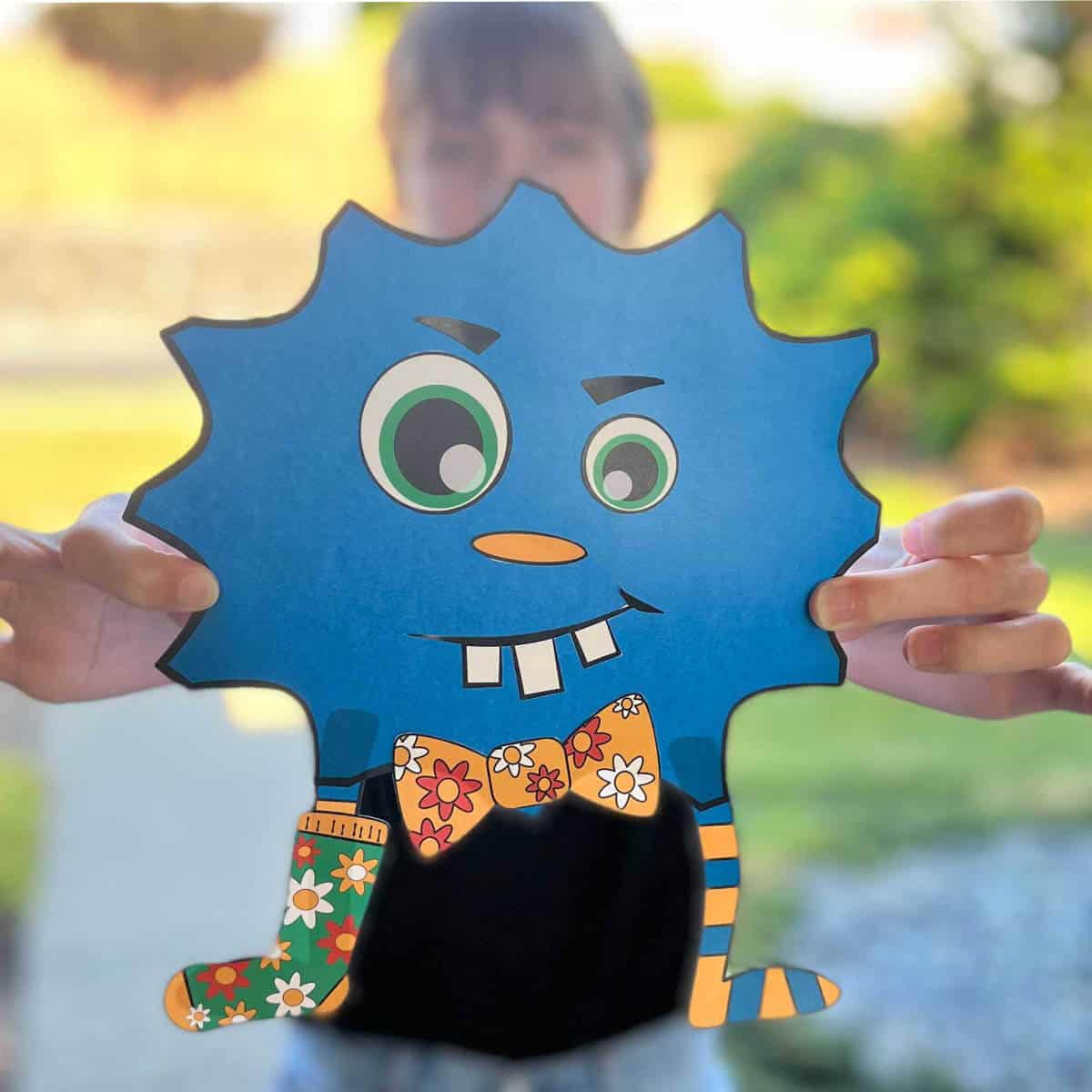 Girl holding a cute blue monster she crafted out of paper printables.