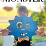 Girl holding a silly blue monster she created with paper monster elements.