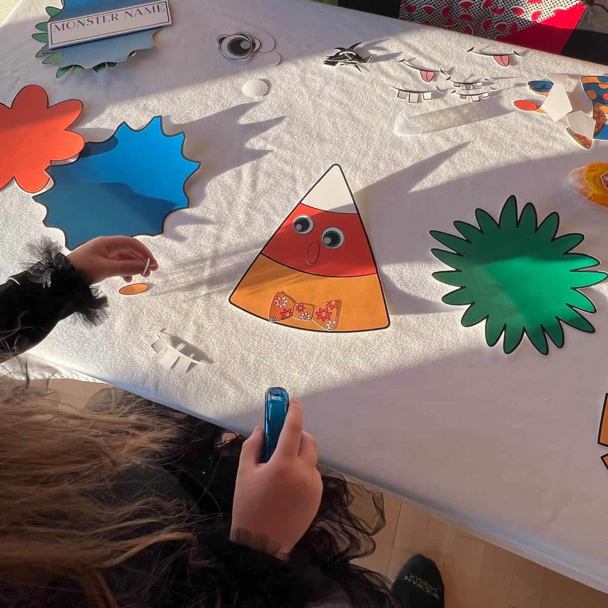 Little girl creating a cute monster using paper monster elements.