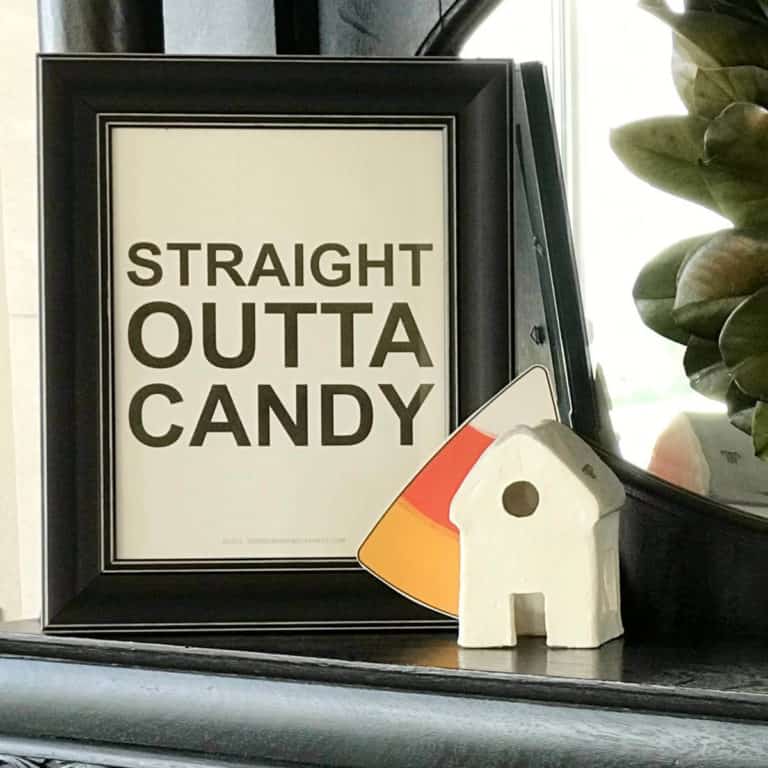 Straight Outta Candy sign on a fireplace next to a ceramic house.