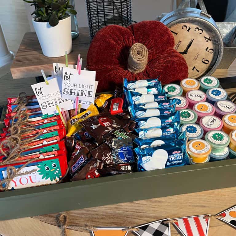 A tray full of items for trick-or-treaters sitting on a table that's decorated for Halloween.