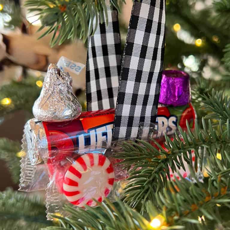 Train made out of candy hanging as an ornament on a Christmas tree.