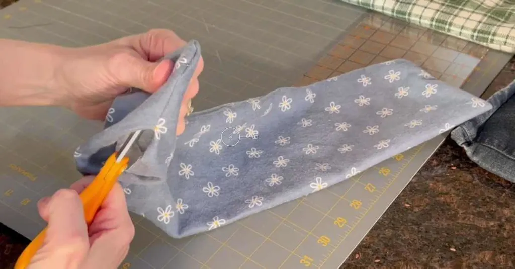 Using scissors to push corners out on a flax seed heating bag so the corners are crisp.