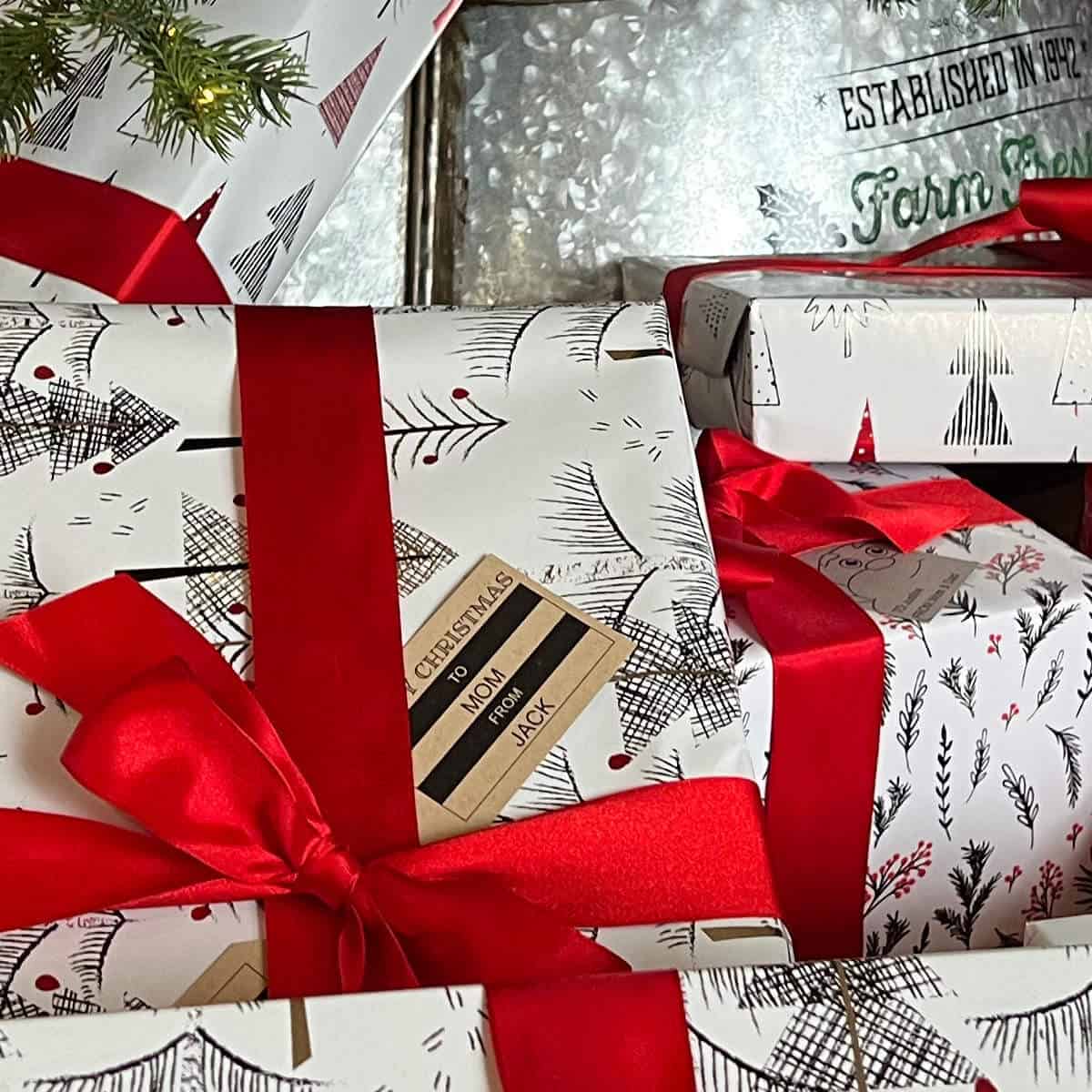 Presents under a Christmas tree wrapped in red ribbon with Christmas gift tags.