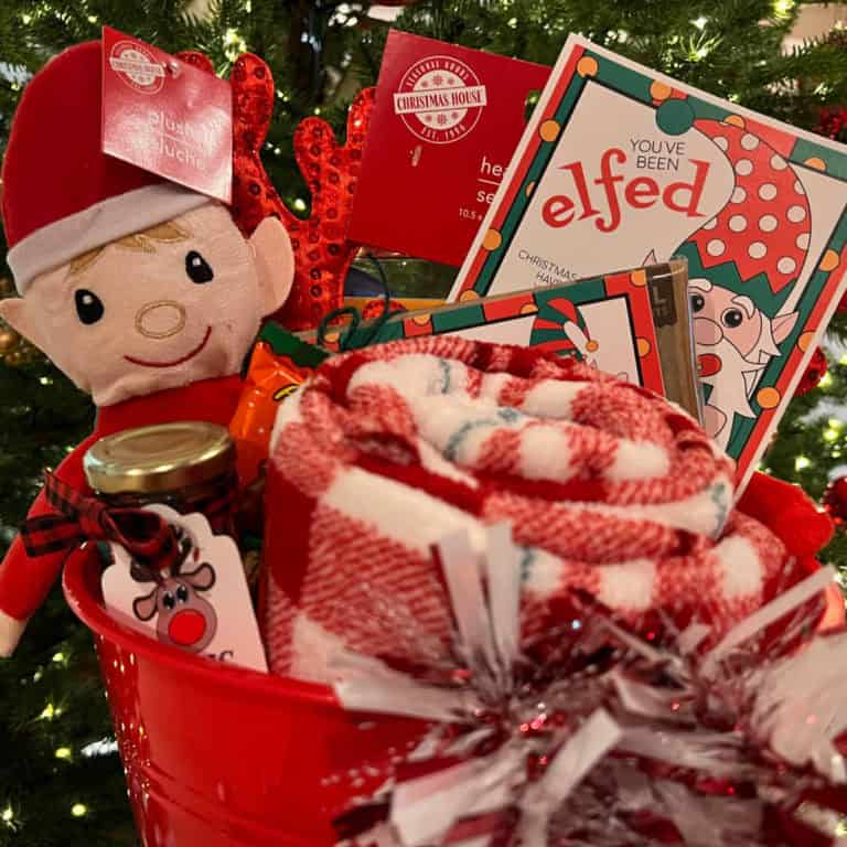 Red bucket full of festive Christmas items and a tag that says, You've Been Elfed.