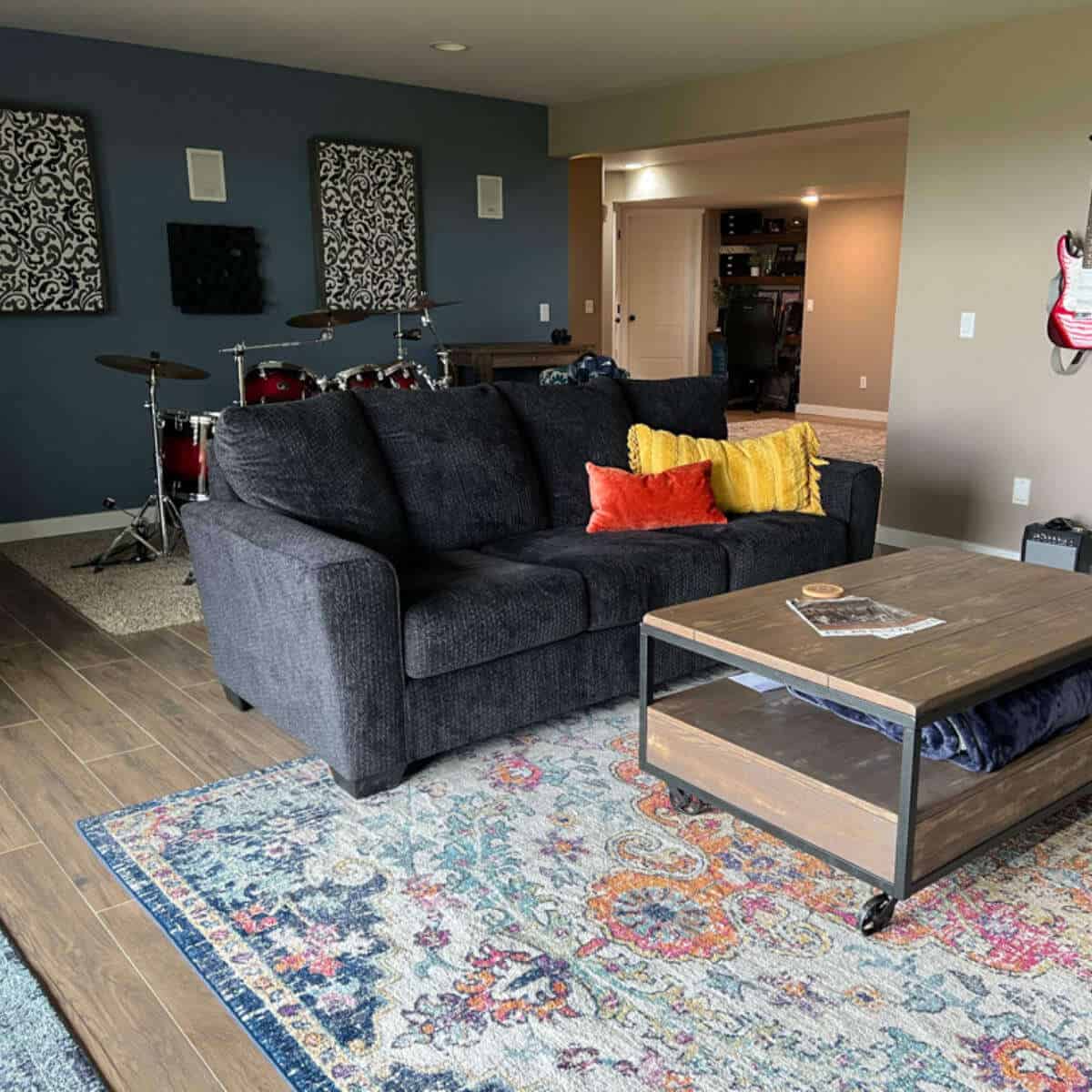 Blue couch in a living space with a rustic coffee table and an area rug.