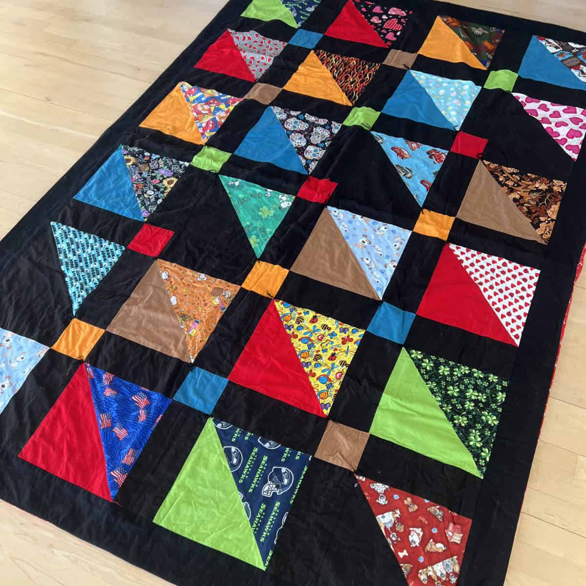 Quilt made out of dog bandanas laying on the floor.