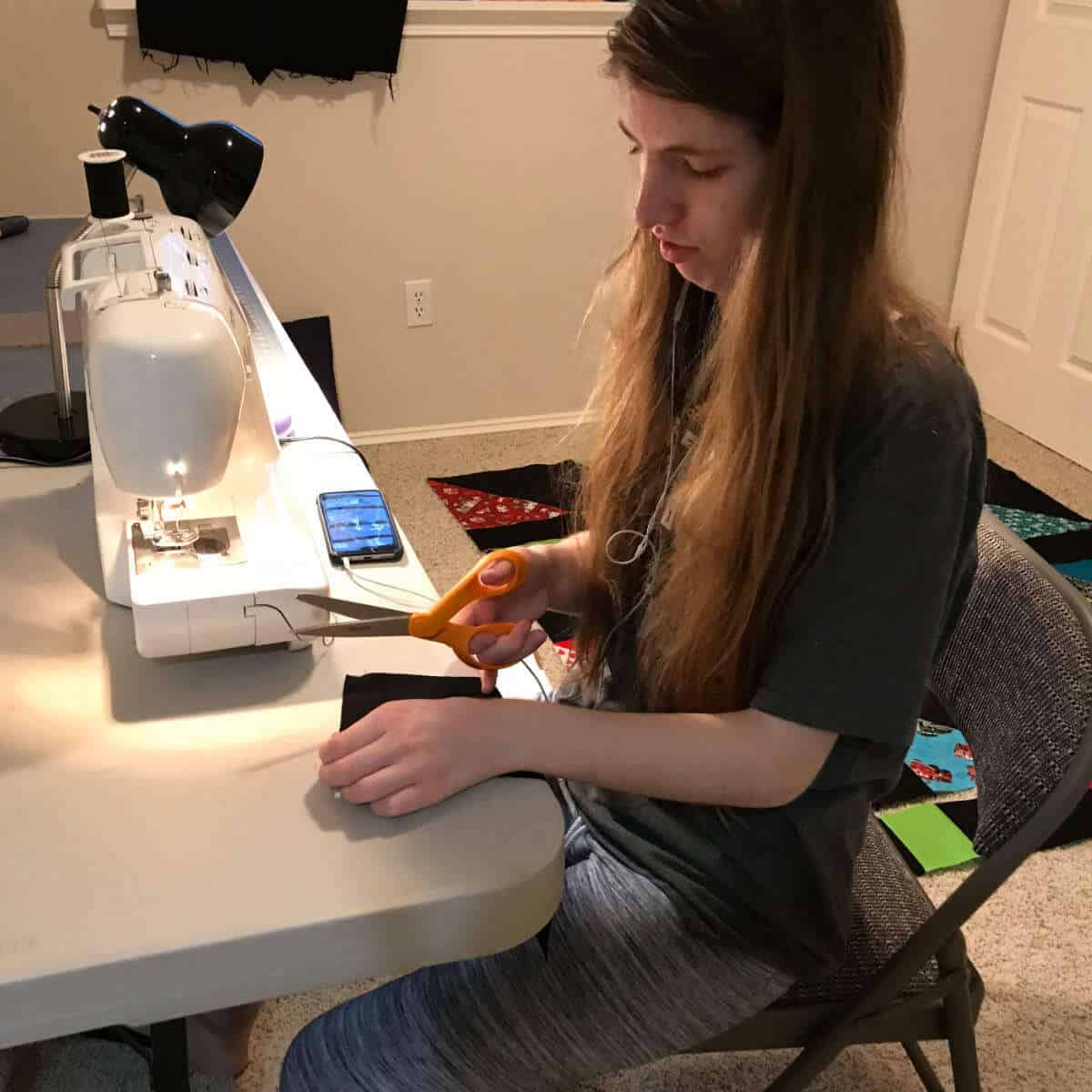 Girl using a sewing machine to make a quilt.